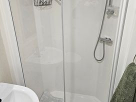 A shower with glass enclosure and sink at Homeslea 33 Millennium Gardens in Morpeth