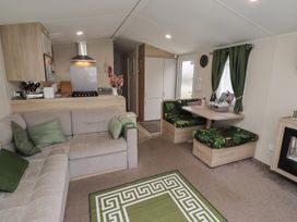 A living room with a sofa, dining table, and kitchen appliances at Homeslea 33 Millennium Gardens in Morpeth