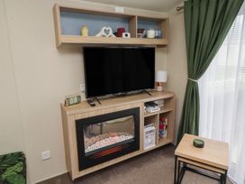 A living room with a television and a fireplace at Homeslea 33 Millennium Gardens Morpeth
