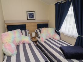A bedroom with two beds, pillows, and a lamp at Homeslea 33 Millennium Gardens in Morpeth
