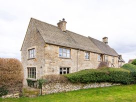 A house with windows and a stone wall at Gardeners Cottage in Chipping Norton