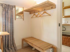 A hallway with a coat rack and bench at Gardeners Cottage in Chipping Norton