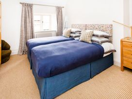 A bedroom with two beds and a bedside table at Gardeners Cottage in Chipping Norton