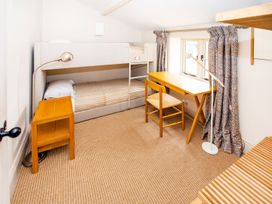 A bedroom with a bunk bed and desk at Gardeners Cottage in Chipping Norton