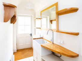 A bathroom with a sink and shelves at Gardeners Cottage in Chipping Norton