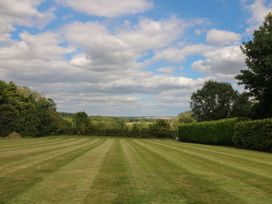 A garden with a lawn and trees at Gardeners Cottage in Chipping Norton