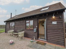 An exterior view of a barn with chairs and a table at The Barn on The Lagoon Droitwich
