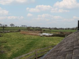 A landscape with grass, trees, water, and reeds at The Barn on The Lagoon Droitwich