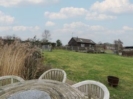 An outdoor area with a table and chairs near a house at The Barn on The Lagoon Droitwich