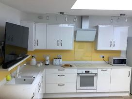 A kitchen with various appliances and cabinets at Woodland Lodge The Snug Filby