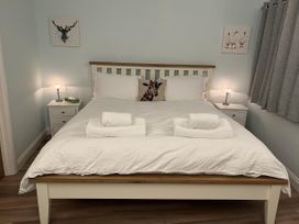 A bedroom with a bed and nightstands at Woodland Lodge The Snug in Filby