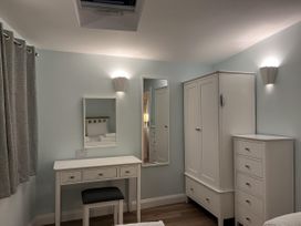 A bedroom with furniture including a wardrobe and vanity table at Woodland Lodge The Snug in Filby