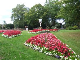 A garden area with flowerbeds and a sign at Woodland Lodge The Snug Filby