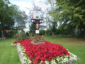 A signpost surrounded by flowers in a garden at Woodland Lodge The Snug Filby