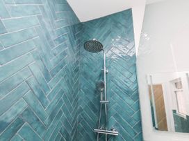 A shower with green tiles and a mirror at Holmwood