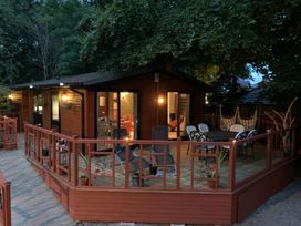A wooden cabin with patio furniture on a deck at The Hermitage in Penrith
