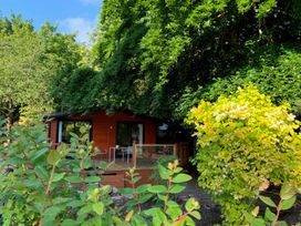 A house with a deck and furniture surrounded by greenery at The Hermitage in Penrith