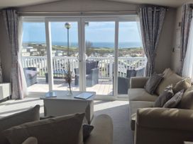 A living room with sliding doors leading to a deck overlooking the sea at 21 Gorse Hill in Exmouth
