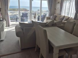 A living room with a dining table and ocean view at 21 Gorse Hill Exmouth