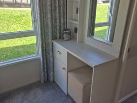 A vanity unit with a mirror and stool in a bedroom at 21 Gorse Hill in Exmouth