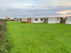 An outdoor area with green grass and three buildings at Chalet 333 California, Norfolk