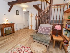 A living room with a staircase and armchair at Ivy Cottage in Abergele