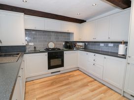 A kitchen with cabinets and appliances at Ivy Cottage in Abergele