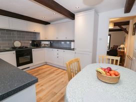 A kitchen with cabinets and a dining table at Ivy Cottage in Abergele