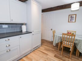A kitchen with cabinets and a table with chairs at Ivy Cottage in Abergele