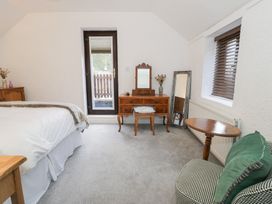 A bedroom with a bed, table, chair, and mirror at Ivy Cottage in Abergele