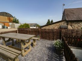 A garden with a wooden table and benches at Ivy Cottage in Abergele