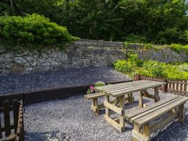 A garden with tables and a stone wall at Ivy Cottage in Abergele