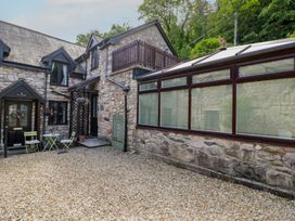 An outdoor area with a stone house and gravel at Ivy Cottage in Abergele