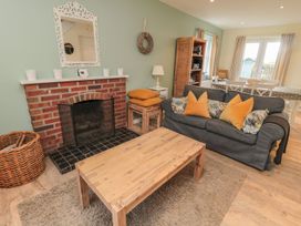 A living room with a fireplace and sofa at Sandy Cove in Chathill