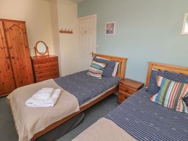 A bedroom with two single beds and wooden furniture at Sandy Cove in Chathill