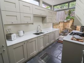 A kitchen with cabinets, sink, kettle, and view of an outdoor area at Tea Tree Cottage in Chipping Campden