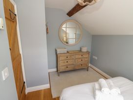 A bedroom with a wooden drawer and a round mirror at Tea Tree Cottage in Chipping Campden