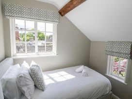 A bedroom with a bed and two windows at Tea Tree Cottage in Chipping Campden