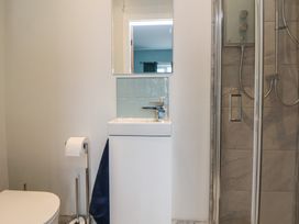 A bathroom with a sink, toilet, shower, and mirror at Mike’s Place in Rhyl