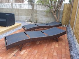 A garden with two sun loungers and an outdoor sofa at Mike’s Place On The Cove Rhyl