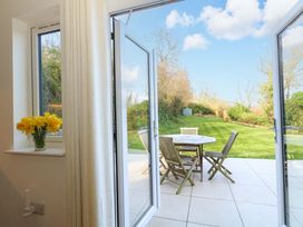 A dining area with a table and chairs overlooking a garden at The Pebble in Dorchester