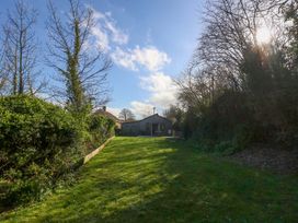 A garden with grass, trees, and a house in the distance at The Pebble in Dorchester
