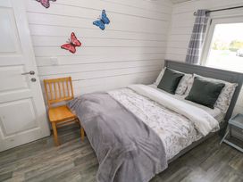 A bedroom with a bed and chair at Nellies Log Cabin in Kilcogy
