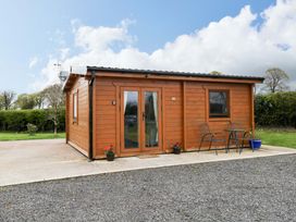 A wooden cabin with chairs and a table outside at Nellies Log Cabin in Kilcogy