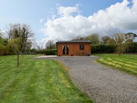A log cabin with a gravel driveway in a garden at Nellies Log Cabin, Kilcogy