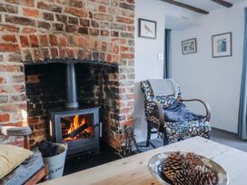 A living room with a fireplace and armchair at 2 Oak Tree Cottages in Marshwood Nr. Hawkchurch