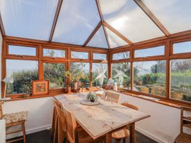 A conservatory with a wooden table and chairs at 2 Oak Tree Cottages in Marshwood Nr. Hawkchurch