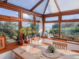 A conservatory with a wooden table and chairs at 2 Oak Tree Cottages in Marshwood Nr. Hawkchurch