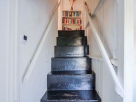A staircase with a bookshelf at the top at 2 Oak Tree Cottages in Marshwood Nr. Hawkchurch