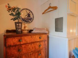A chest of drawers with a vase and plate in a bedroom at 2 Oak Tree Cottages Marshwood Nr. Hawkchurch